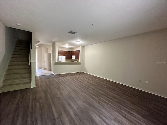 unfurnished living room featuring dark hardwood / wood-style flooring and a textured ceiling