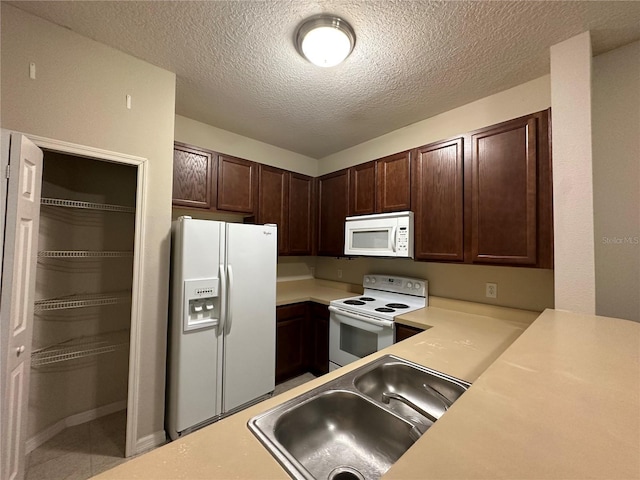 kitchen with sink, white appliances, dark brown cabinets, and a textured ceiling