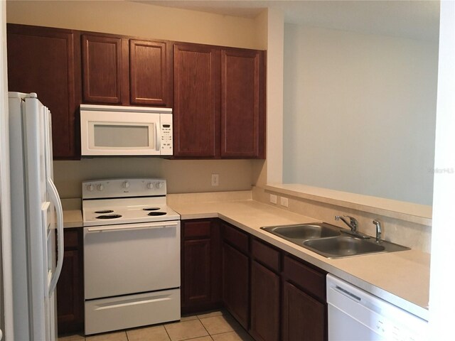 kitchen featuring light tile patterned flooring, white appliances, and sink