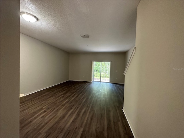 unfurnished room featuring dark wood-type flooring and a textured ceiling