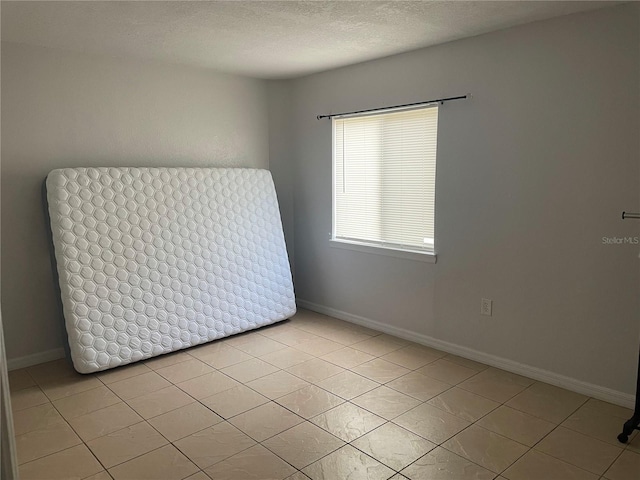 spare room featuring light tile patterned floors and a textured ceiling