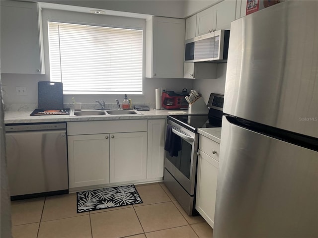 kitchen with light tile patterned floors, stainless steel appliances, sink, and white cabinets