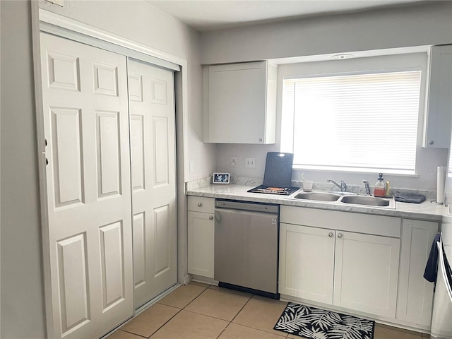 kitchen featuring light tile patterned flooring, sink, stainless steel dishwasher, and white cabinets