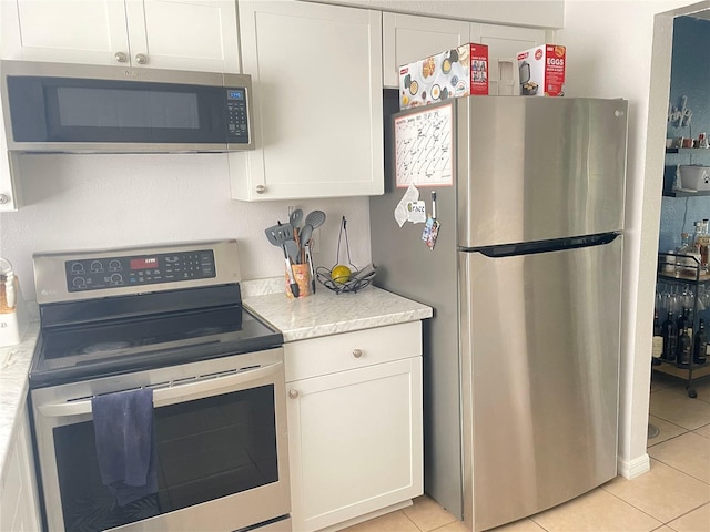 kitchen featuring appliances with stainless steel finishes, light tile patterned floors, and white cabinets