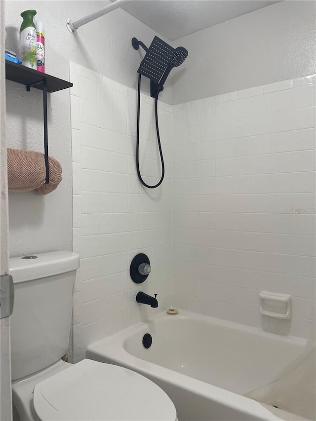 bathroom with tiled shower / bath combo and toilet