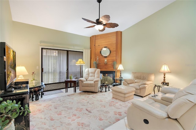 tiled living room with ceiling fan, a large fireplace, and vaulted ceiling