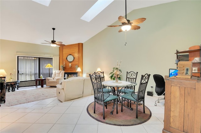 dining area with ceiling fan, vaulted ceiling with skylight, and light tile patterned floors