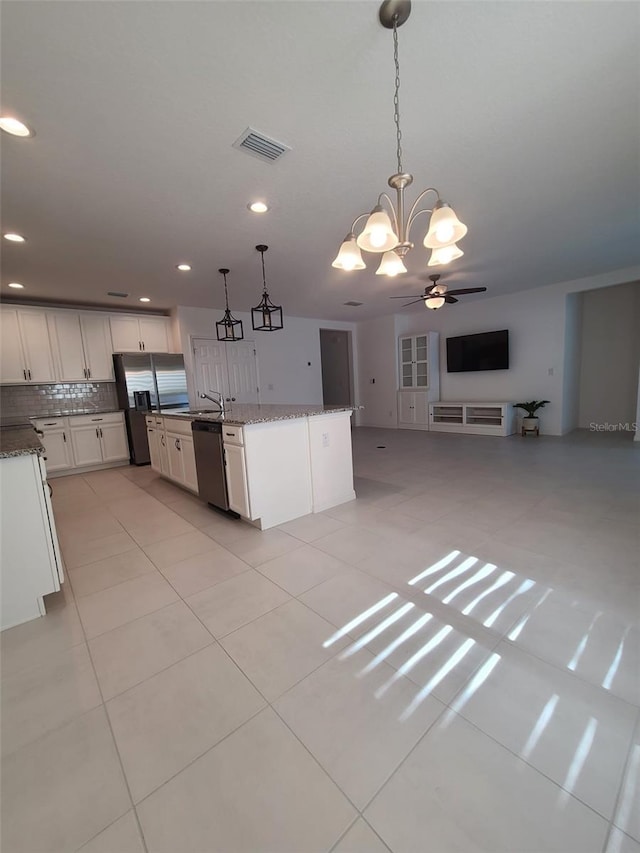 kitchen featuring pendant lighting, stainless steel appliances, an island with sink, and white cabinets