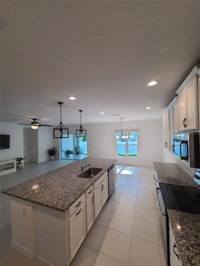 kitchen featuring sink, a center island with sink, appliances with stainless steel finishes, dark stone counters, and white cabinets