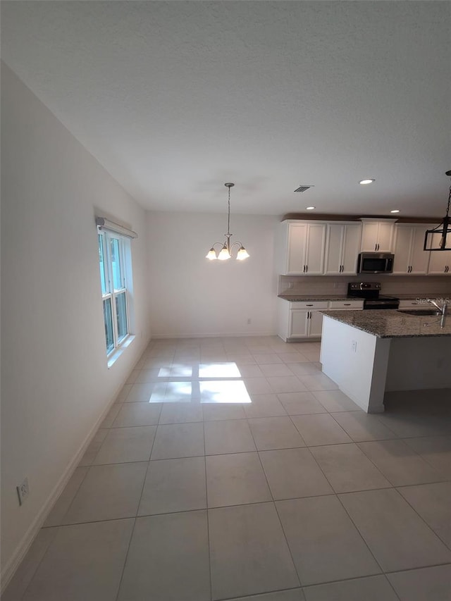 kitchen featuring light tile patterned flooring, hanging light fixtures, electric range, dark stone counters, and white cabinets