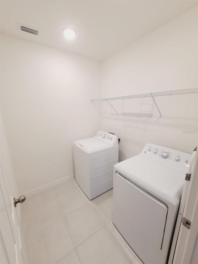 laundry room with light tile patterned floors and washer and clothes dryer