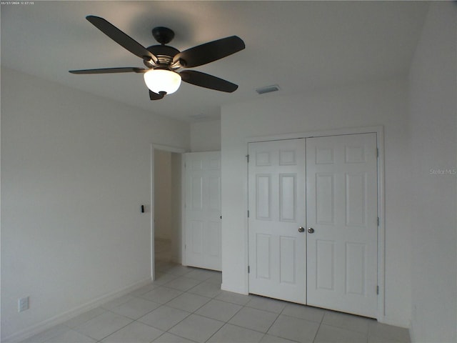 unfurnished bedroom with light tile patterned flooring, ceiling fan, and a closet