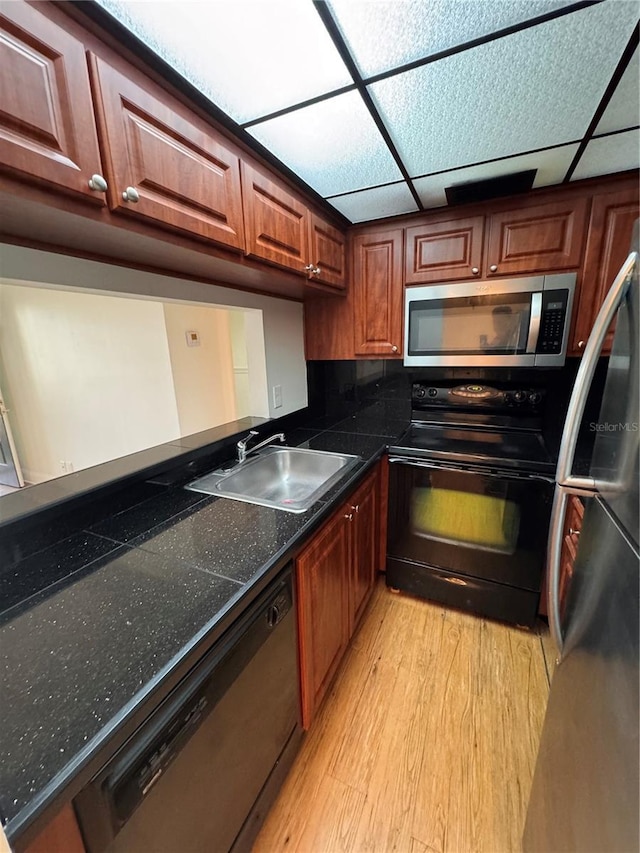 kitchen featuring appliances with stainless steel finishes, sink, a drop ceiling, and light wood-type flooring