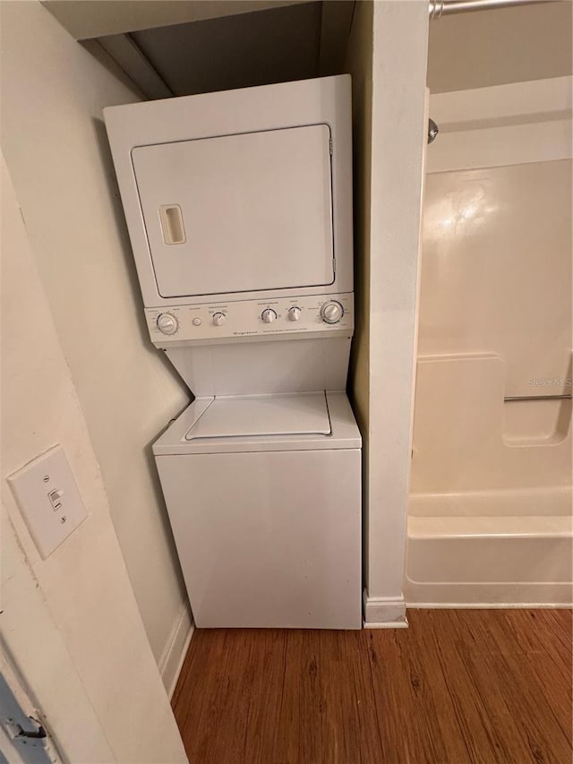 washroom featuring dark hardwood / wood-style flooring and stacked washer and dryer