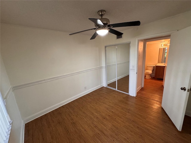 unfurnished bedroom featuring dark hardwood / wood-style flooring, ceiling fan, a closet, and a textured ceiling