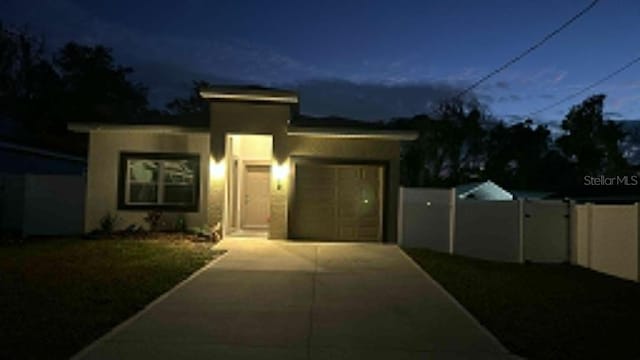 view of front of home with concrete driveway, fence, and a garage