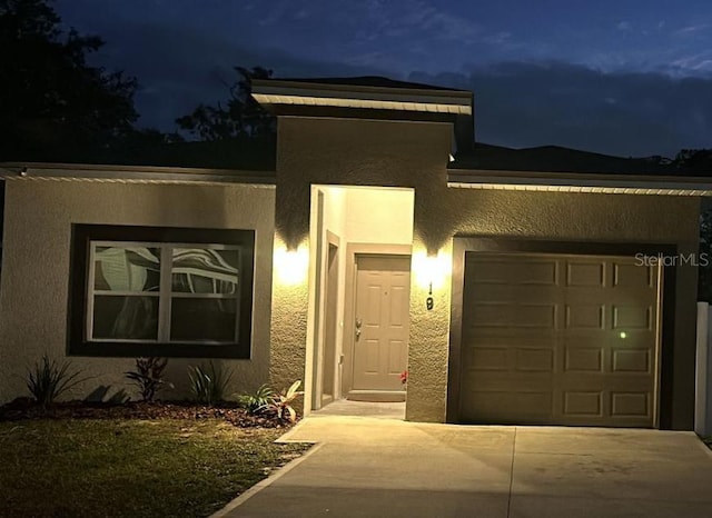 view of front of house with a garage, concrete driveway, and stucco siding