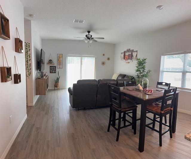 dining room featuring ceiling fan, plenty of natural light, a textured ceiling, and dark hardwood / wood-style flooring