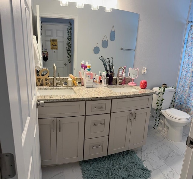 full bath featuring a sink, toilet, marble finish floor, and double vanity