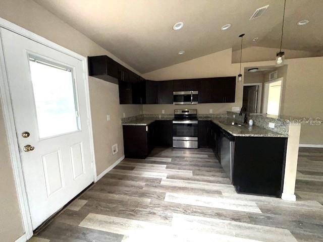 kitchen featuring hanging light fixtures, vaulted ceiling, stainless steel appliances, and sink