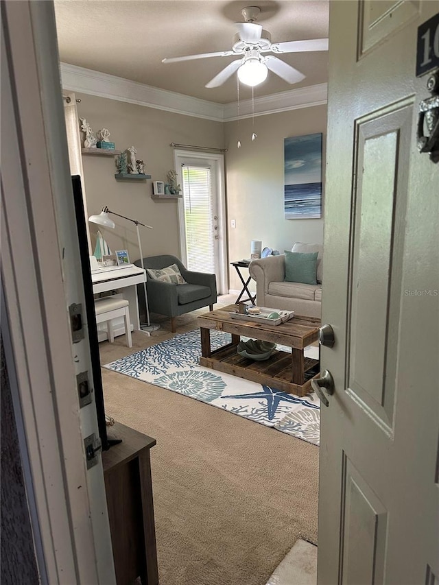 living room with crown molding, ceiling fan, and carpet