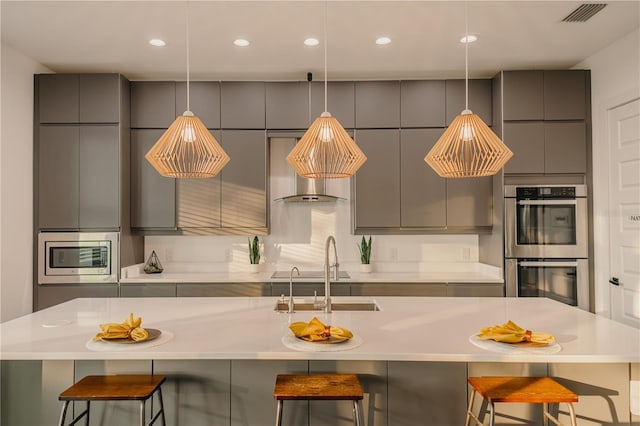 kitchen featuring sink, gray cabinets, a kitchen breakfast bar, and stainless steel appliances