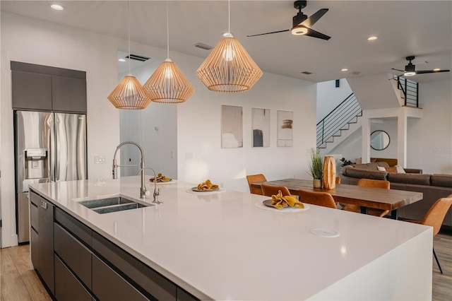 kitchen with pendant lighting, sink, a large island, and stainless steel fridge with ice dispenser