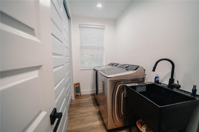 washroom with washing machine and dryer, wood-type flooring, and sink