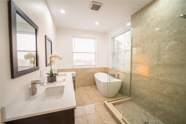 bathroom featuring shower with separate bathtub, plenty of natural light, and tile walls