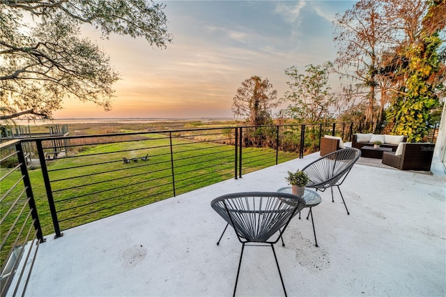 patio terrace at dusk with an outdoor hangout area and a lawn