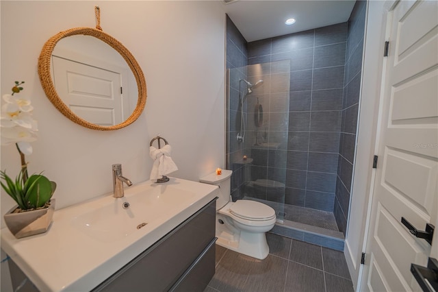 bathroom featuring vanity, tile patterned flooring, toilet, and a tile shower