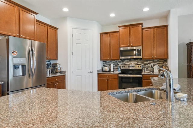 kitchen featuring tasteful backsplash, appliances with stainless steel finishes, sink, and light stone counters