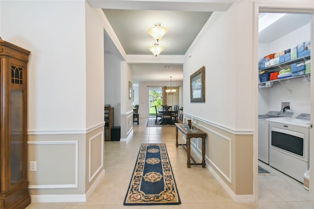 interior space featuring washer and dryer, light tile patterned floors, a notable chandelier, and a textured ceiling