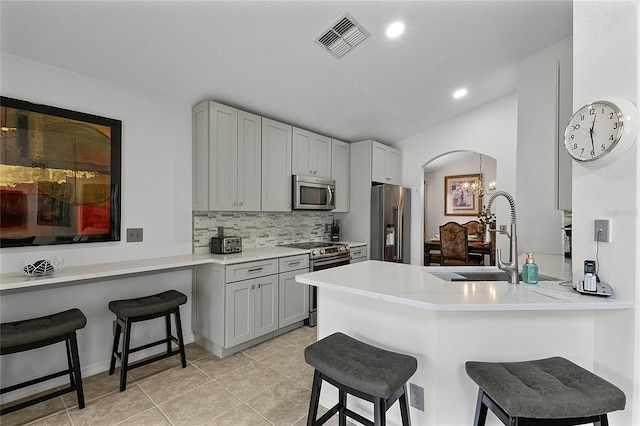 kitchen with appliances with stainless steel finishes, kitchen peninsula, and a breakfast bar area