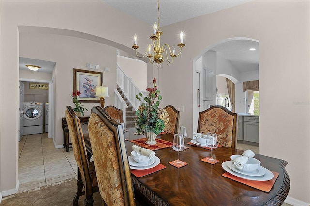 tiled dining room with an inviting chandelier, washer and clothes dryer, and a textured ceiling