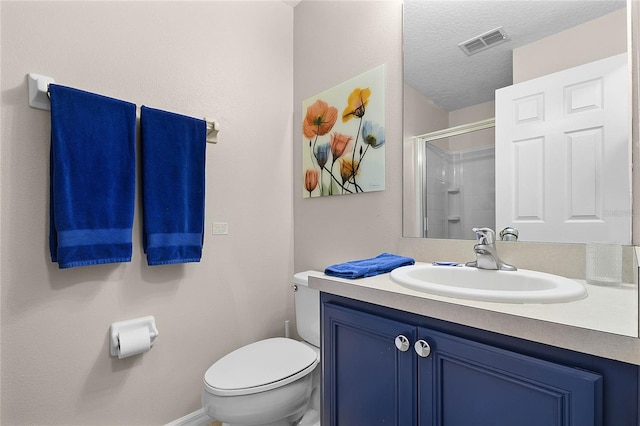 bathroom featuring vanity, toilet, an enclosed shower, and a textured ceiling