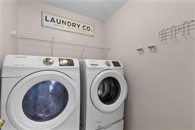 laundry area with independent washer and dryer and a textured ceiling