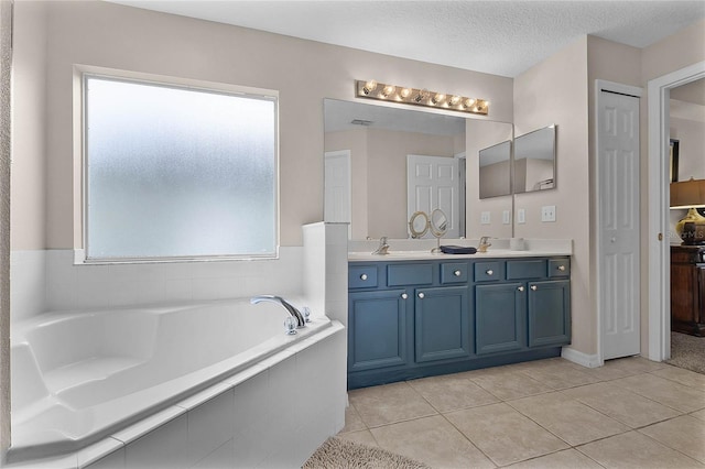 bathroom featuring a relaxing tiled tub, vanity, tile patterned flooring, and a textured ceiling