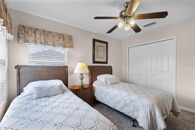 bedroom featuring multiple windows, dark carpet, ceiling fan, and a closet