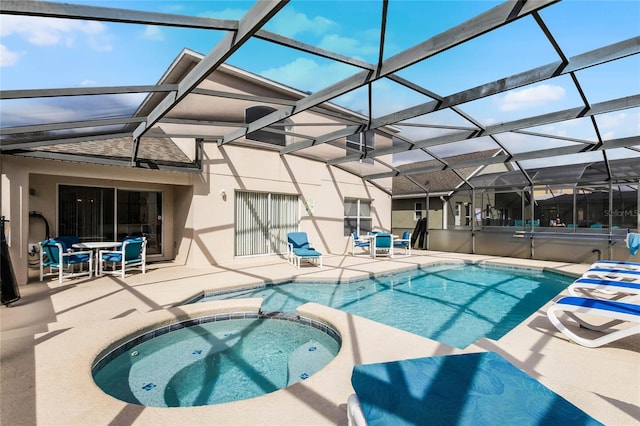 view of swimming pool with an in ground hot tub, glass enclosure, and a patio area