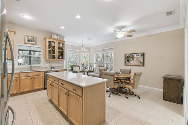 kitchen with sink, crown molding, appliances with stainless steel finishes, a kitchen island, and light brown cabinets