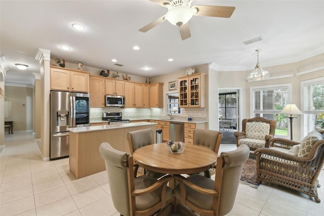 tiled dining area with ornamental molding, sink, and ceiling fan