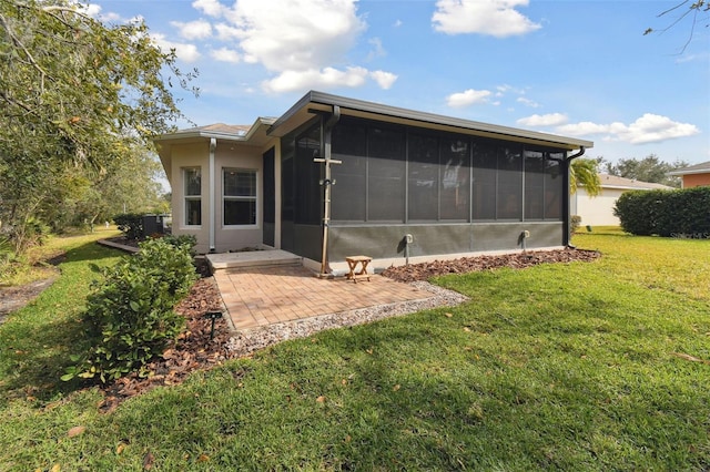 rear view of house featuring a patio, a sunroom, and a lawn