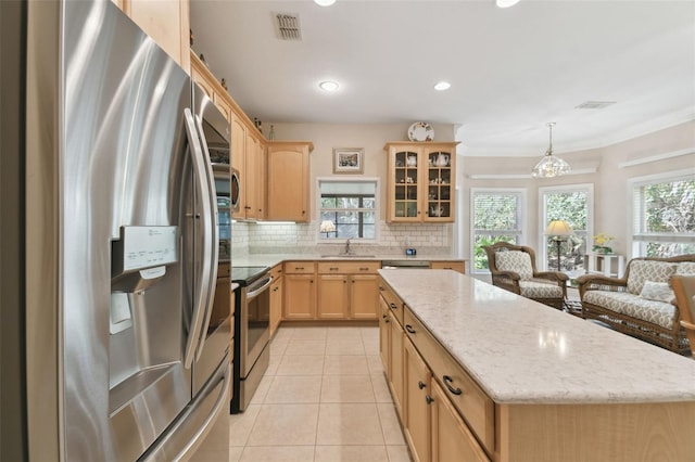 kitchen featuring tasteful backsplash, light tile patterned floors, light brown cabinets, a kitchen island, and stainless steel appliances