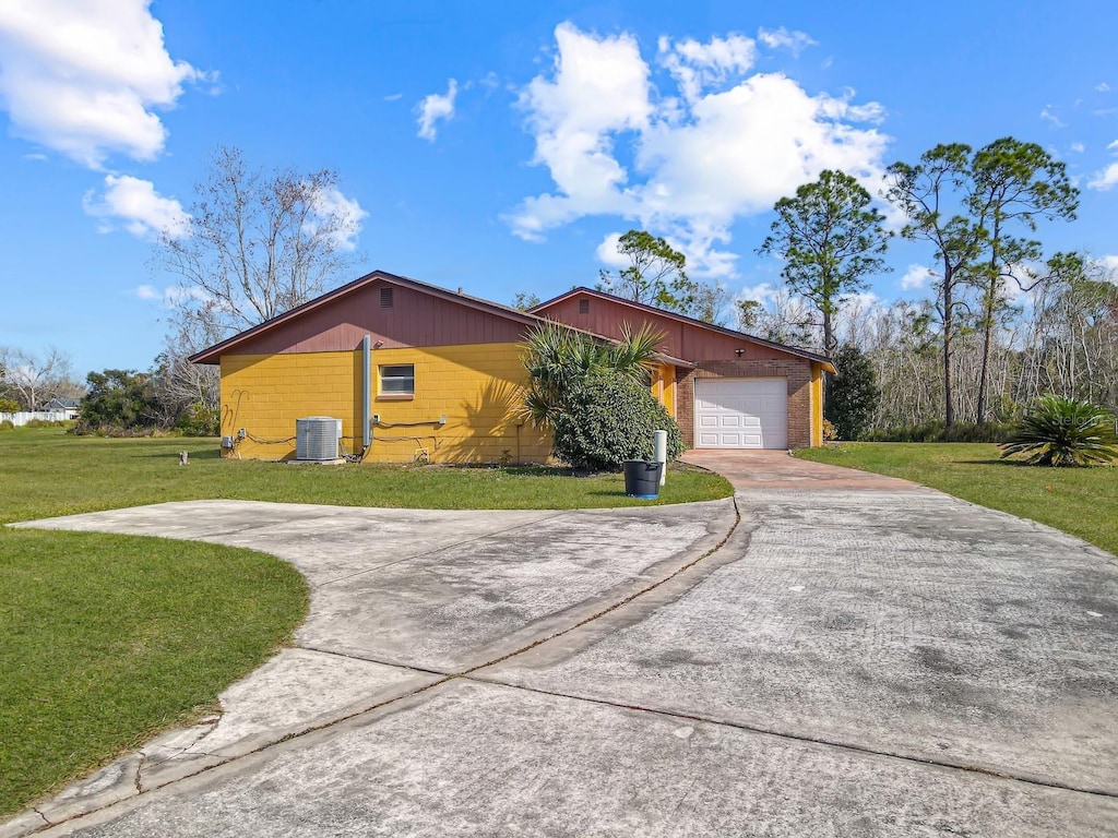 view of side of home featuring a garage, a yard, and central air condition unit