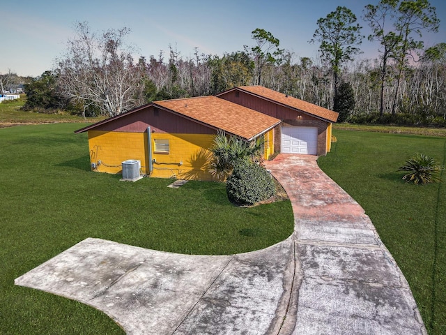 view of front of home featuring a garage, central air condition unit, and a front lawn