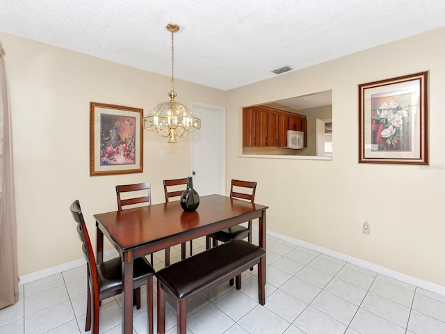 tiled dining room featuring an inviting chandelier and a textured ceiling