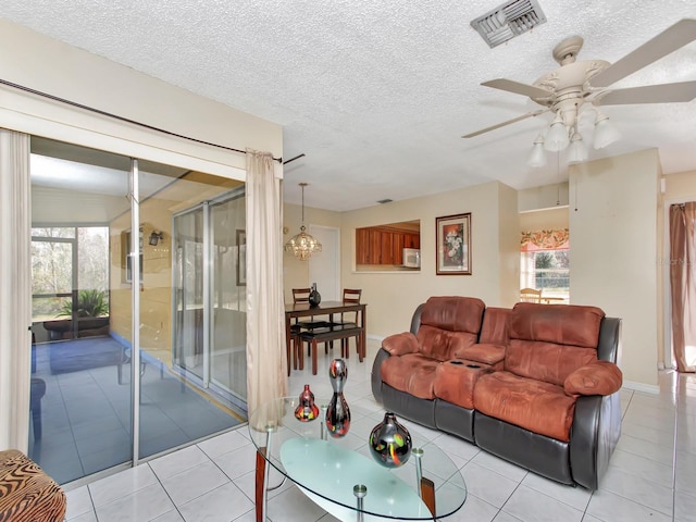 living room with light tile patterned flooring, ceiling fan, and a textured ceiling