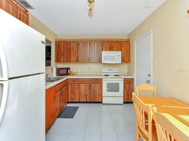 kitchen with light tile patterned flooring, white appliances, and sink