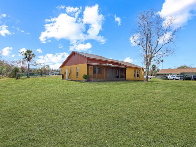 rear view of property featuring a yard and a sunroom